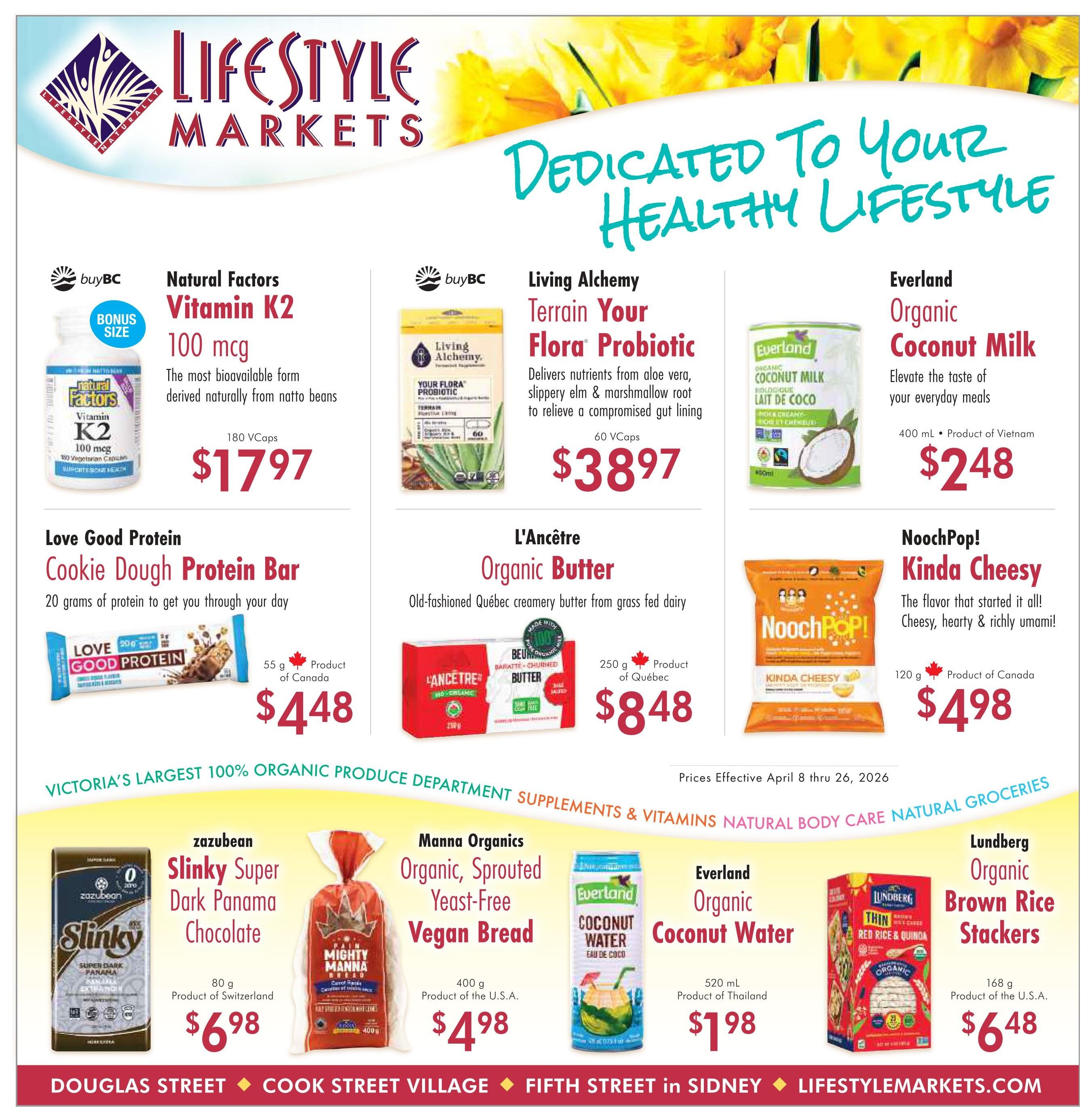 Lifestyle Markets flyer page 1 featuring dedicated to your healthy lifestyle specials. Offers include Natural Factors Vitamin K2 100 mcg for $17.97, Living Alchemy Terrain Your Flora Probiotic 60 VCaps for $38.97, and Everland Organic Coconut Milk 400 mL for $2.48. Also featured are Love Good Protein Cookie Dough Protein Bar 55 g for $4.48, L'Ancêtre Organic Butter 250 g for $8.48, and NoochPop! Kinda Cheesy 120 g for $4.98. The bottom section highlights Victoria's largest 100% organic produce department, supplements, vitamins, natural body care, and natural groceries. Products include zazubean Slinky Super Dark Panama Chocolate 80 g for $6.98, Manna Organics Organic, Sprouted Yeast-Free Vegan Bread 400 g for $4.98, Everland Organic Coconut Water 520 mL for $1.98, and Lundberg Organic Brown Rice Stackers 168 g for $6.48. Prices are effective April 8 through April 26, 2026.