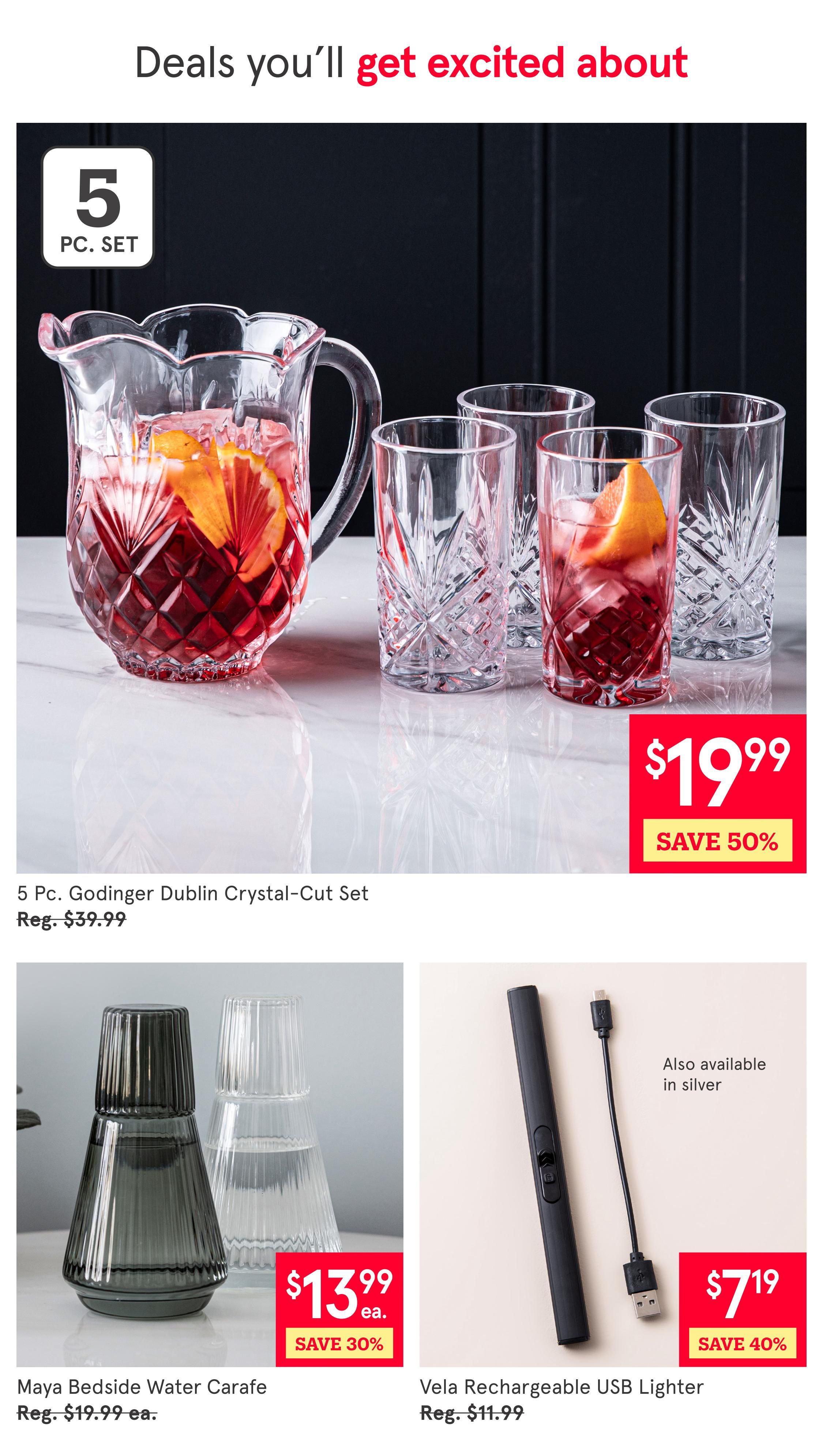 Kitchen Stuff Plus flyer page 7 featuring deals. Top item is a 5 Pc. Godinger Dublin Crystal-Cut Set for $19.99, saving 50% off the regular price of $39.99. Below, the Maya Bedside Water Carafe is on sale for $13.99 each, a 30% saving from the regular price of $19.99 each. To the right, the Vela Rechargeable USB Lighter is available for $7.19, saving 40% off the regular price of $11.99. This lighter is also available in silver.