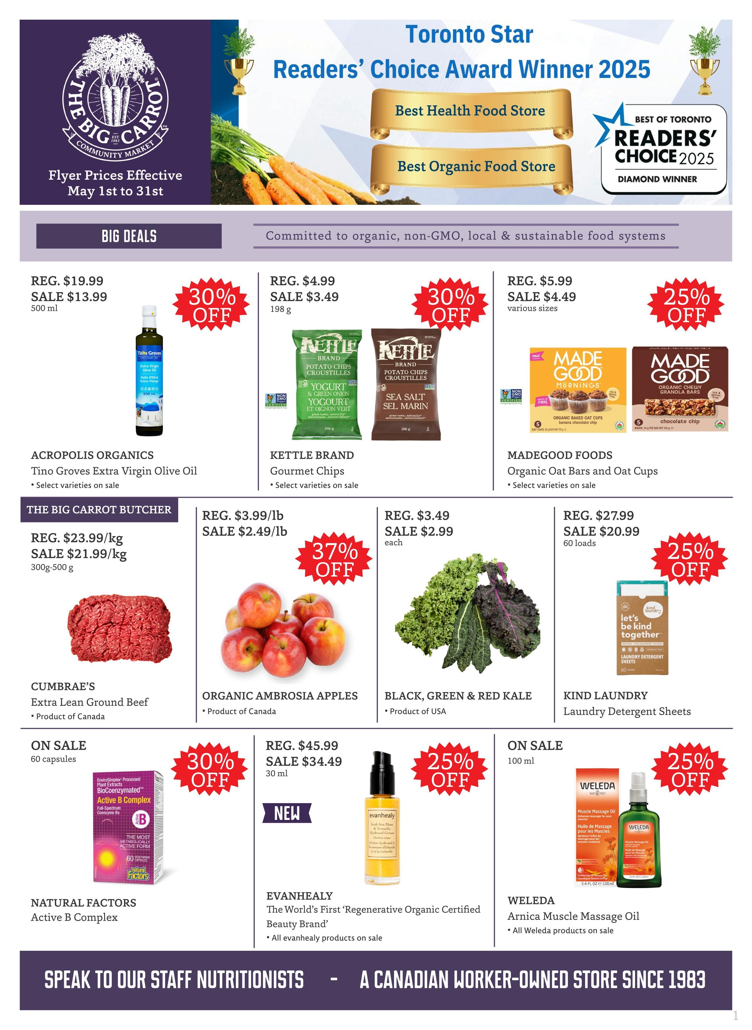 The Big Carrot Community Market flyer specials from May 1st to 31st. Featured products include Acropolis Organics Tino Groves Extra Virgin Olive Oil on sale for $13.99 (regular $19.99) for 500 ml, a 30% discount. Kettle Brand Gourmet Chips are on sale for $3.49 (regular $4.99) for 198 g, with select varieties on sale. Madegood Foods Organic Oat Bars and Oat Cups are on sale for $4.49 (regular $5.99) in various sizes, with a 25% discount. The Big Carrot Butcher offers Extra Lean Ground Beef from Cumbraes for $21.99/kg (regular $23.99/kg) in 300g-500g packages. Organic Ambrosia Apples are on sale for $2.49/lb (regular $3.99/lb), a 37% discount. Black, Green & Red Kale from the USA is on sale for $2.99 each. Kind Laundry Detergent Sheets are on sale for $20.99 (regular $27.99) for 60 loads, a 25% discount. Natural Factors Active B Complex is on sale for 60 capsules with a 30% discount. Evanhealy The World's First Regenerative Organic Certified Beauty Brand products are on sale, including a serum for $34.49 (regular $45.99) for 30 ml. Weleda Arnica Muscle Massage Oil is on sale for 100 ml with a 25% discount. The flyer highlights The Big Carrot as a Toronto Star Readers' Choice Award Winner 2025 for Best Health Food Store and Best Organic Food Store. It also states 'Committed to organic, non-GMO, local & sustainable food systems' and 'Speak to our staff nutritionists - A Canadian worker-owned store since 1983.