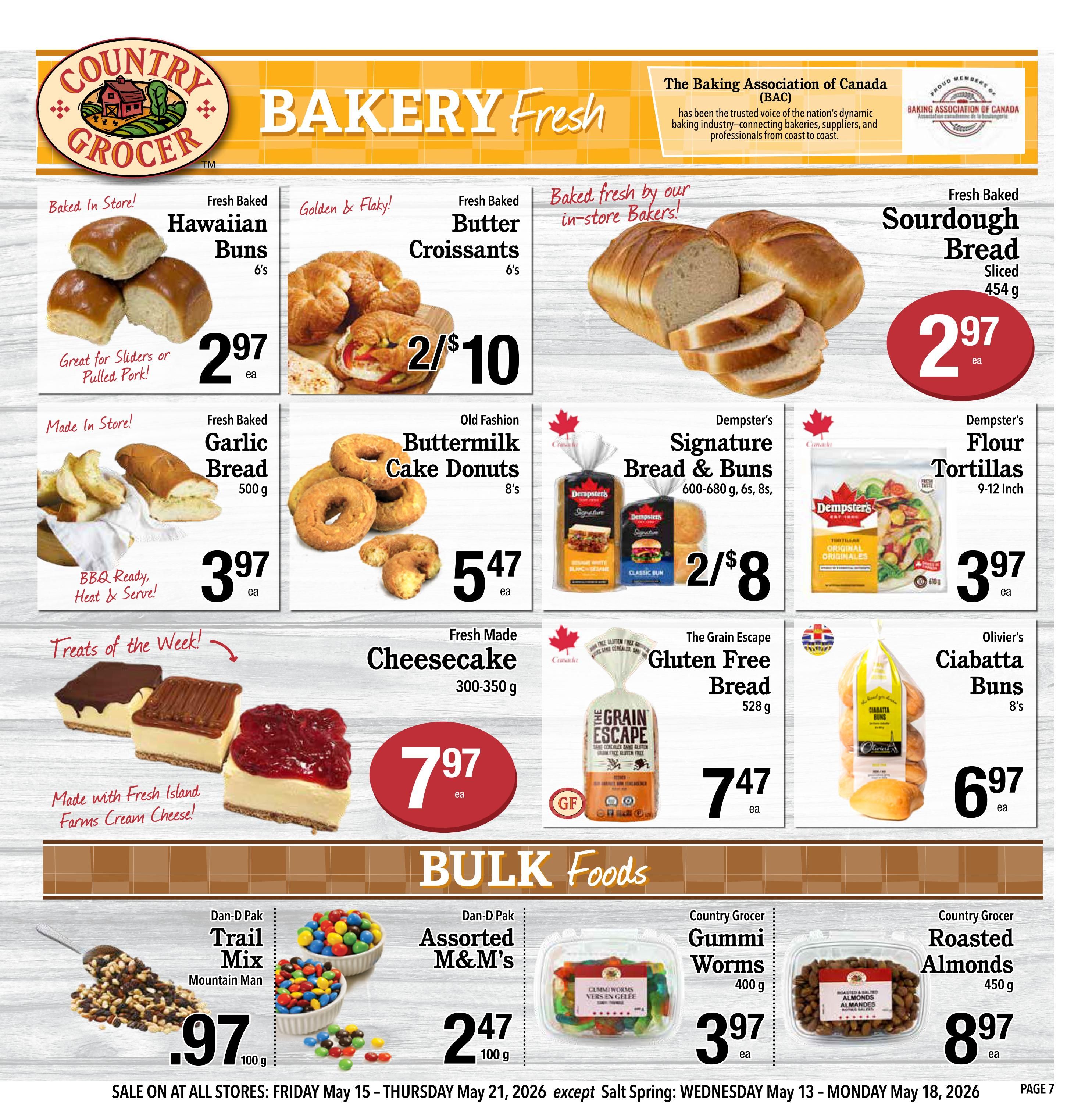 Country Grocer Weekly Flyer Specials Page 7. Featuring fresh baked goods including Hawaiian Buns for $2.97, Butter Croissants for 2 for $10, and Sourdough Bread for $2.97. Also available are fresh baked Garlic Bread for $3.97, Old Fashion Buttermilk Cake Donuts for $5.47, Dempster's Signature Bread & Buns for 2 for $8, Dempster's Flour Tortillas for $3.97, The Grain Escape Gluten Free Bread for $7.47, and Olivier's Ciabatta Buns for $6.97. Treats of the Week include Cheesecake for $7.97, made with Fresh Island Farms Cream Cheese. Bulk Foods section includes Dan-D Pak Trail Mix for $0.97, Dan-D Pak Assorted M&M's for $2.47, Country Grocer Gummi Worms for $3.97, and Country Grocer Roasted Almonds for $8.97. Sale runs from Friday, May 15 to Thursday, May 21, 2026.