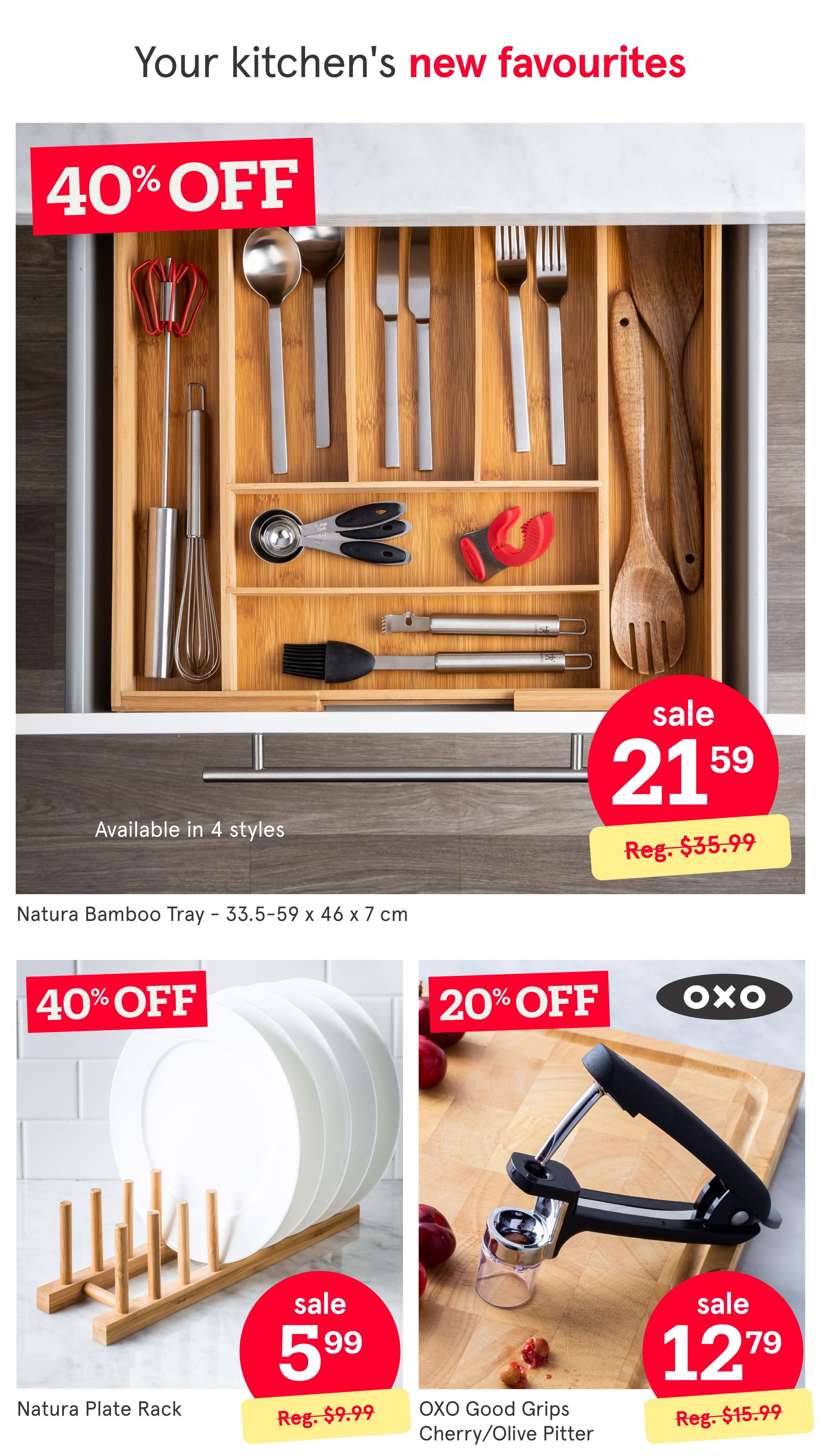 Kitchen Stuff Plus flyer page 2 featuring kitchen new favourites. A Natura Bamboo Tray is on sale for $21.59 (regularly $35.99) and is available in 4 styles. The tray dimensions are 33.5-59 x 46 x 7 cm. Also featured is a Natura Plate Rack on sale for $5.99 (regularly $9.99). An OXO Good Grips Cherry/Olive Pitter is 20% off, selling for $12.79 (regularly $15.99).